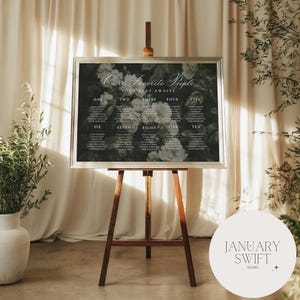 May include: A seating plan displayed on a wooden easel. The chart has floral details and the text "Our Favorite People" and "Your Seat Awaits." Names are listed under numbers one to ten. The January Swift Studio logo is in the bottom right corner.