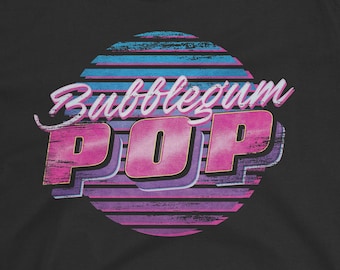 Può includere: T-shirt nera con un design retrò. Le parole "Bubblegum POP" sono in rosa e bianco, su un cerchio a strisce blu e viola. Il marchio "SNAXTIME" è stampato in alto.