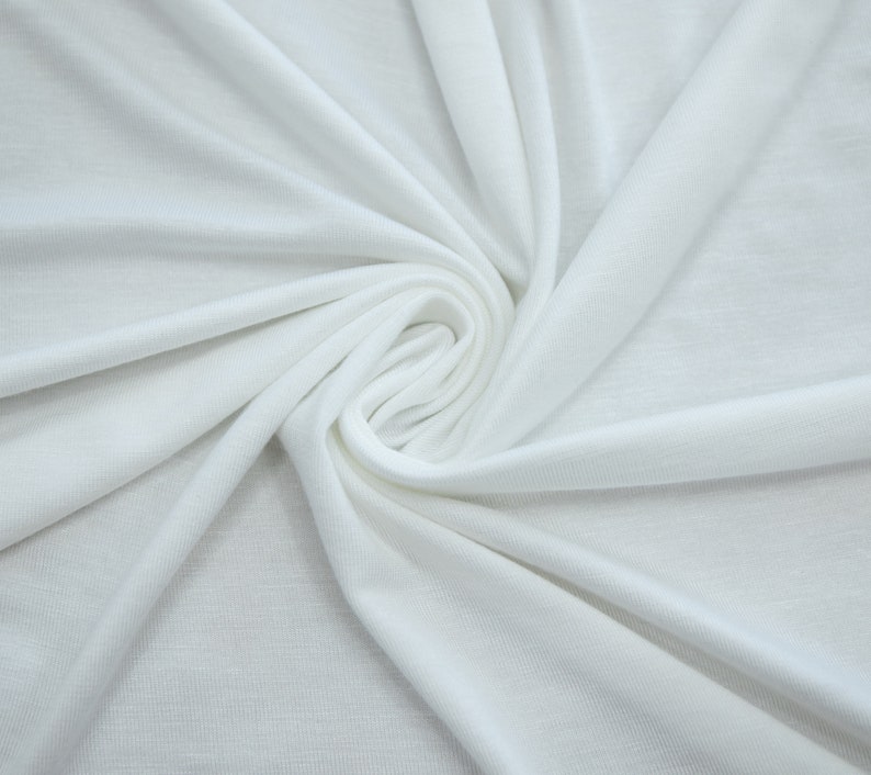 K&ouml;nnte beinhalten: Wei&szlig;er Stoff mit einer glatten, weichen Textur. Der Stoff ist gefaltet und spiralf&ouml;rmig drapiert.