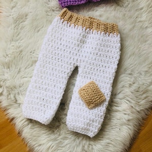 May include: White crocheted baby pants with a tan crocheted waistband and a tan crocheted patch on the leg.