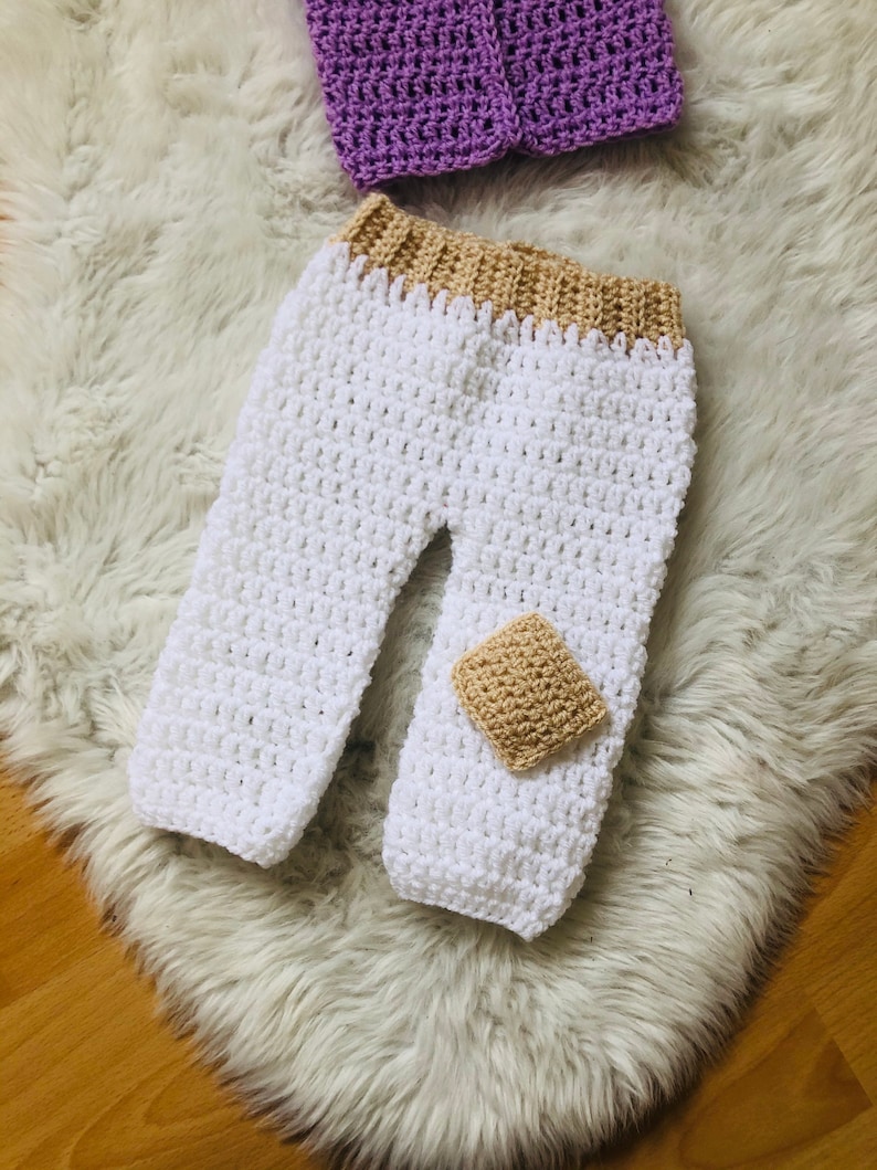 May include: White crocheted baby pants with a tan crocheted waistband and a tan crocheted patch on the leg.