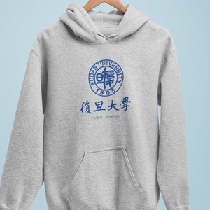 以下が含まれることがあります： 前面に青い復旦大学のロゴが付いた灰色のフード付きスウェットシャツ。ロゴには、中国語と英語で大学の名称と1905年が記載されています。