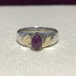 May include: A silver ring with a purple gemstone and gold leaf accents.