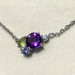 May include: A silver chain necklace with a purple, green, and blue gemstone pendant.