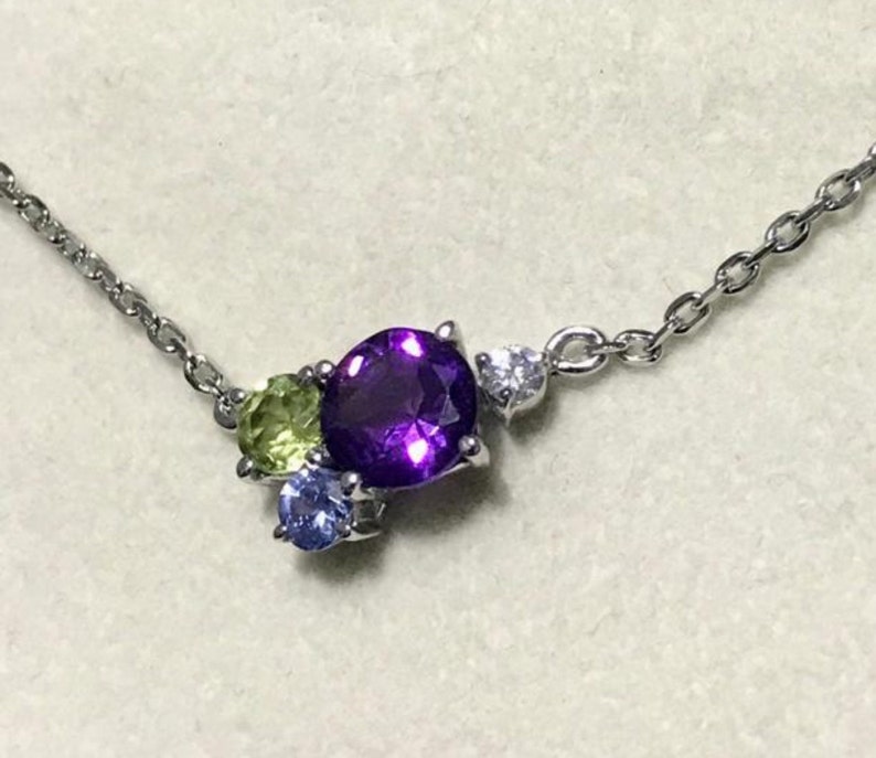 May include: A silver chain necklace with a purple, green, and blue gemstone pendant.