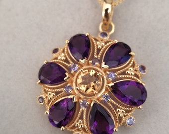 May include: A gold necklace with a pendant featuring a flower design with purple and yellow gemstones.