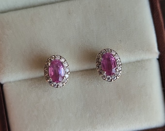 May include: A pair of earrings with pink oval gemstones surrounded by a halo of smaller white gemstones.