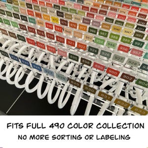 May include: A clear plastic organiser with numbered colour swatches. The organiser has white loops and holds a large collection of colours. Text at the bottom reads "FITS FULL 490 COLOR COLLECTION NO MORE SORTING OR LABELING."