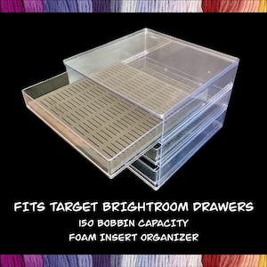 May include: Clear plastic organizer with a drawer partially extended, featuring a gray foam insert. The text on the image reads: "FITS TARGET BRIGHTROOM DRAWERS, 150 BOBBIN CAPACITY, FOAM INSERT ORGANIZER."