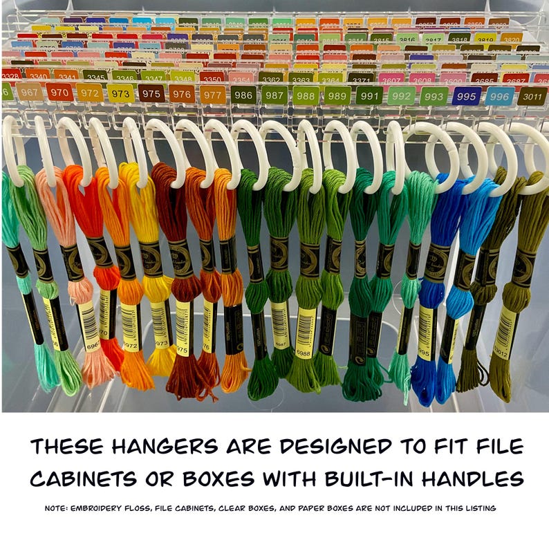 May include: A selection of embroidery floss in various colours, displayed on white hangers. The floss is arranged in a rainbow of hues, from greens and blues to oranges and yellows. The image text reads: "THESE HANGERS ARE DESIGNED TO FIT FILE CABINETS OR BOXES WITH BUILT-IN HANDLES."