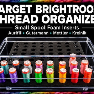 May include: A clear acrylic thread organizer with the text "TARGET BRIGHTROOM THREAD ORGANIZER". The organizer holds small spools of thread in various colors, including teal, purple, and orange. The organizer has a black foam insert.
