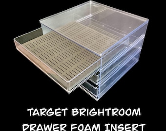 May include: Clear plastic storage drawer with a removable tan foam insert. The drawer is partially open, revealing the interior. The text "TARGET BRIGHTROOM DRAWER FOAM INSERT" is printed in white.
