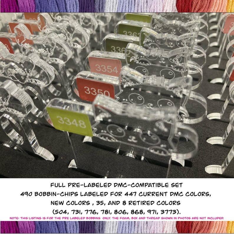 May include: A clear acrylic bobbin-chip set for cross-stitch embroidery. The set includes 490 pre-labeled chips for 447 current DMC colors, 35 new colors, and 8 retired colors. Each chip has a number label. The text "FULL PRE-LABELED DMC-COMPATIBLE SET" is visible.