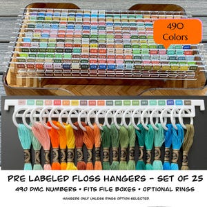 May include: A display of embroidery floss organized by color on white hangers. The image shows a set of 25 pre-labeled floss hangers with 490 DMC numbers. The text on the image says "PRE LABELED FLOSS HANGERS - SET OF 25".