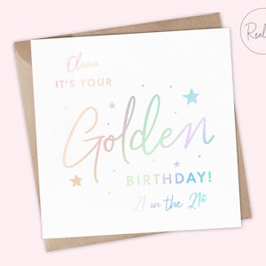 May include: A white card with a holographic rainbow design that says "Olivia, it's your Golden Birthday! 21 on the 21st".