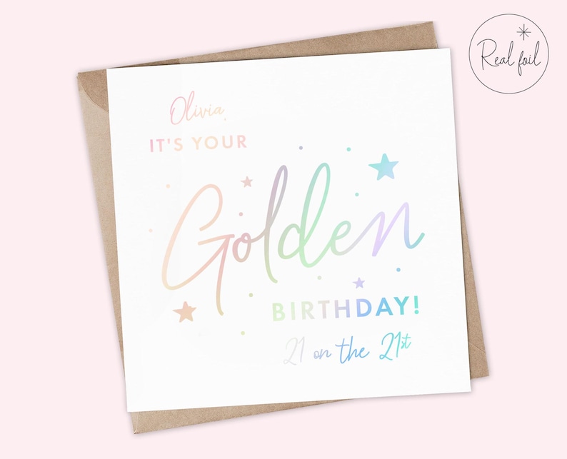 May include: A white card with a holographic rainbow design that says "Olivia, it's your Golden Birthday! 21 on the 21st".