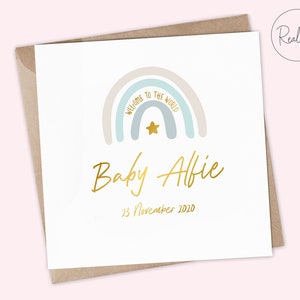 Puede incluir: Una tarjeta blanca con un dise&ntilde;o de arco&iacute;ris en tonos azul, rosa y beige. El arco&iacute;ris tiene las palabras "Welcome to the World" escritas en &eacute;l. Una estrella dorada est&aacute; en el centro del arco&iacute;ris. El texto "Baby Alfie" est&aacute; escrito en cursiva dorada debajo del arco&iacute;ris. La fecha "23 de noviembre de 2020" est&aacute; escrita en dorado debajo del nombre.