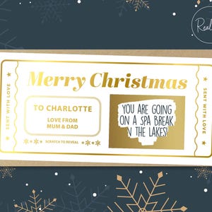 May include: A gold foil Christmas scratch-off card with the text "Merry Christmas" and "To Charlotte, Love from Mum & Dad." The scratch-off area reveals "You are going on a spa break in the Lakes!" The card is on a dark blue background with gold snowflakes.