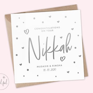 May include: A white card with silver foil lettering that says "Congratulations on your Nikkah. Mudasir & Rimsha 10.10.2020". The card is decorated with silver foil hearts and dots.