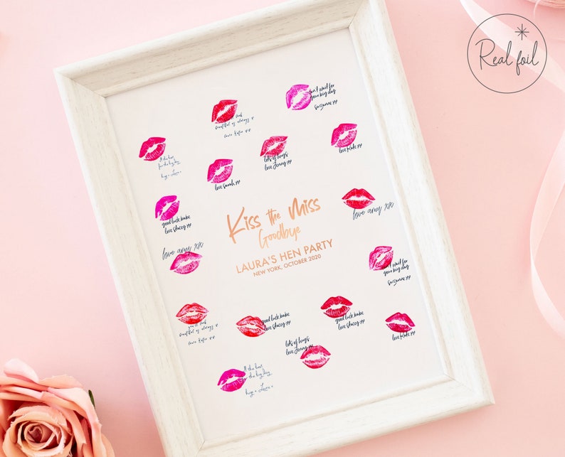 以下が含まれることがあります： ピンクの背景に白い額縁で飾られたプリント。金色の文字で「Kiss the Miss Goodbye」と書かれている。プリントには唇のプリントのデザインと「Laura's Hen Party, New York, October 2020」というテキストが書かれている。