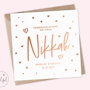 May include: A white card with rose gold foil lettering that says "Congratulations on your Nikkah. Mudasir & Rimsha 10.10.2020". The card is decorated with small rose gold hearts and dots.