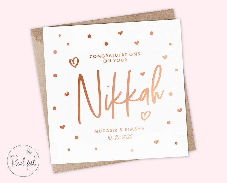 May include: A white card with rose gold foil lettering that says "Congratulations on your Nikkah. Mudasir & Rimsha 10.10.2020". The card is decorated with small rose gold hearts and dots.