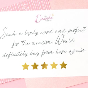 Op de afbeelding: Een witte kaart met een handgeschreven recensie die luidt: "Such a lovely card and perfect for the occasion. Would definitely buy from here again." Vijf gouden sterren staan onder de recensie. De kaart ligt op een roze-wit gestreepte achtergrond.