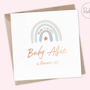 Puede incluir: Una tarjeta blanca con un dise&ntilde;o de arco&iacute;ris y el texto "Bienvenido al mundo" en azul claro. El arco&iacute;ris tiene una estrella en el centro. Debajo del arco&iacute;ris est&aacute; el texto "Baby Alfie" en cobre y la fecha "23 de noviembre de 2010".