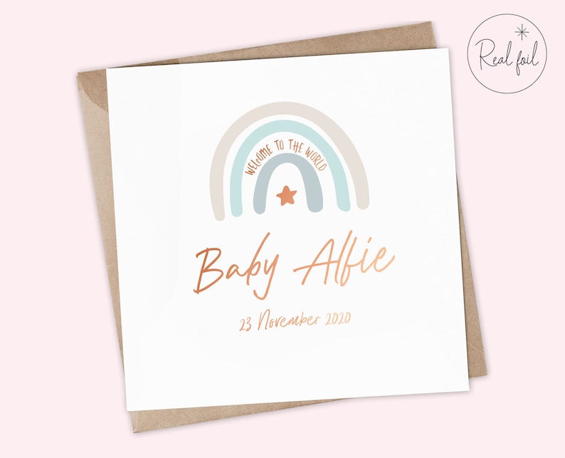 Puede incluir: Una tarjeta blanca con un dise&ntilde;o de arco&iacute;ris y el texto "Bienvenido al mundo" en azul claro. El arco&iacute;ris tiene una estrella en el centro. Debajo del arco&iacute;ris est&aacute; el texto "Baby Alfie" en cobre y la fecha "23 de noviembre de 2010".