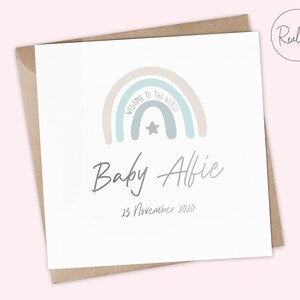 Puede incluir: Una tarjeta blanca con un dise&ntilde;o de arco&iacute;ris y el texto "Bienvenido al mundo" en gris claro. El arco&iacute;ris est&aacute; en tonos beige, azul claro y gris. Hay una peque&ntilde;a estrella gris en el centro del arco&iacute;ris. Debajo del arco&iacute;ris est&aacute; el texto "Baby Alfie" en una fuente cursiva gris y la fecha "23 de noviembre de 2020" en una fuente gris m&aacute;s peque&ntilde;a.
