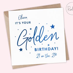 May include: A white card with blue foil lettering that says "Olivia, It's your Golden Birthday! 21 on the 21st". The card has a brown envelope.