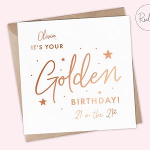 May include: A white card with gold foil lettering that says "Olivia, It's your Golden Birthday! 21 on the 21st".