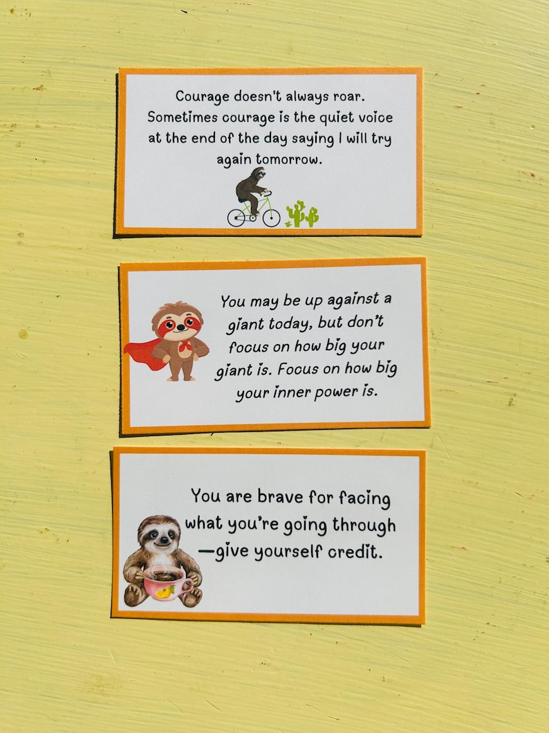 May include: Three rectangular cards with orange borders and white backgrounds. Each card features a different motivational quote with illustrations of sloths. The top card has a sloth riding a bicycle. The middle card has a sloth wearing a cape. The bottom card has a sloth holding a cup.