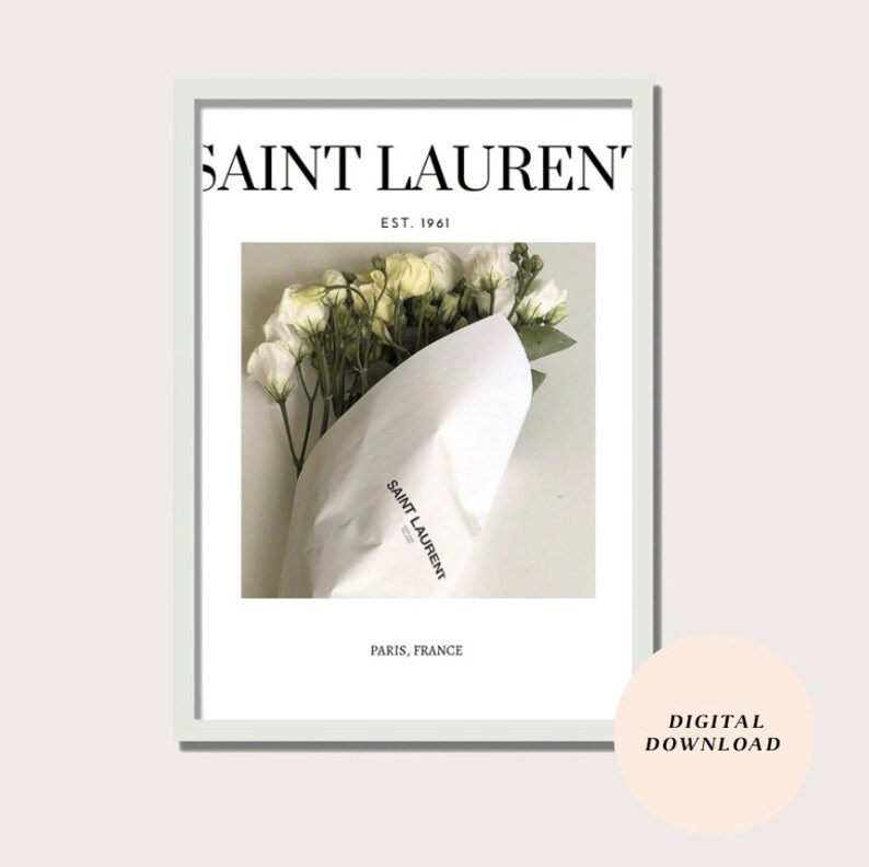May include: A white framed print with the text "SAINT LAURENT" in black, "EST. 1961" in smaller black text, and "PARIS, FRANCE" in black text. The print features a photo of a bouquet of white flowers wrapped in white paper with the "SAINT LAURENT" logo printed on the paper.