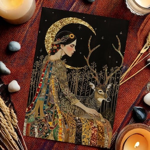 May include: An art print featuring a woman with a deer, set against a black background with a gold crescent moon. The print is surrounded by lit candles, stones, and wheat stalks on a red and orange patterned textile.