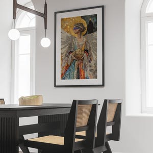 May include: A framed collage artwork featuring a woman with a blindfold, holding a basket of fruit. The artwork is set against a white wall with a black dining table and chairs in the foreground.
