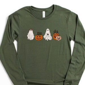 May include: A long-sleeved, army green t-shirt with a graphic of three ghosts and three pumpkins. The ghosts are wearing floral crowns and the pumpkins have stems and leaves.