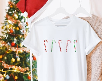 May include: White t-shirt with a red and green candy cane design. The shirt is hanging on a white hanger with a red Santa hat on top.