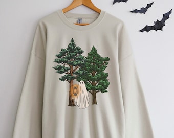 Op de afbeelding: Een lichtbeige sweatshirt met een grafische print van een geest die voor twee groene bomen staat. De geest draagt een lantaarn om zijn nek.
