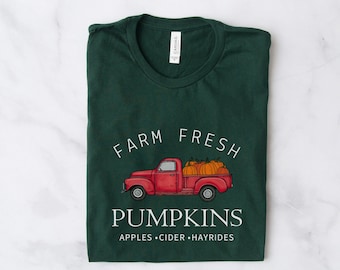 May include: A green t-shirt with a white graphic of a red pickup truck carrying pumpkins. The text "Farm Fresh Pumpkins Apples Cider Hayrides" is printed below the truck.