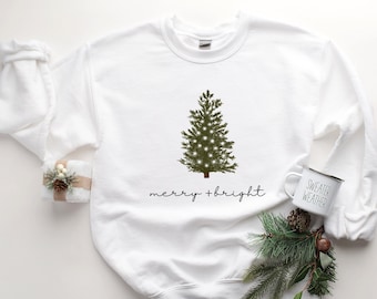 Może przedstawiać: Biała świąteczna bluza z zielonym drzewem bożonarodzeniowym i napisem "merry + bright".