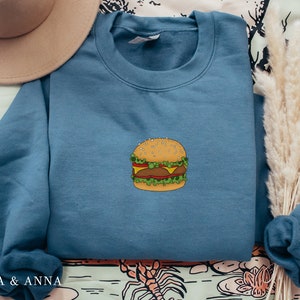 May include: A blue sweatshirt with a cartoon illustration of a hamburger on the front.