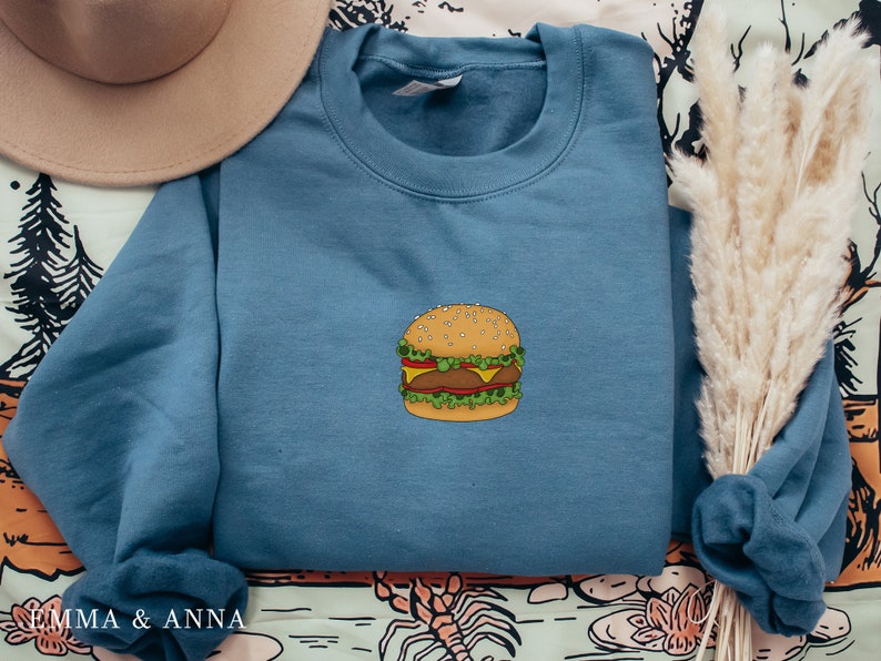 May include: A blue sweatshirt with a cartoon illustration of a hamburger on the front.