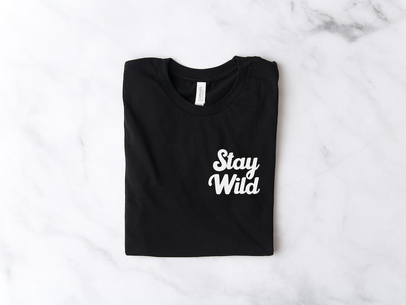 May include: Black t-shirt with white text that says "Stay Wild" in a retro font.