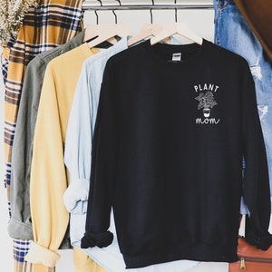 May include: Black sweatshirt with a white graphic of a potted plant and the text "PLANT MOM".