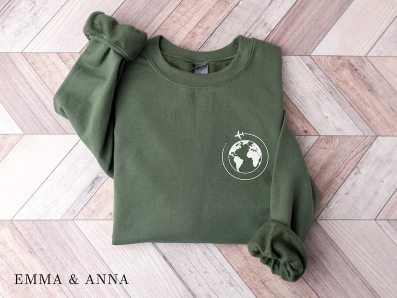 May include: A green sweatshirt with a white graphic of a globe with airplanes flying around it.