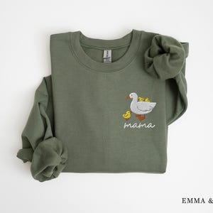 May include: A green sweatshirt with an embroidered design of a goose with goslings and the word "mama" underneath.