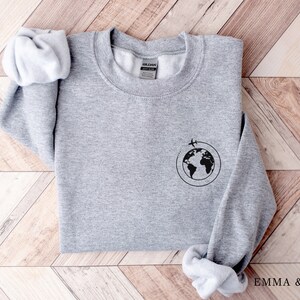 May include: Gray sweatshirt with a black graphic of a globe with airplanes flying around it.