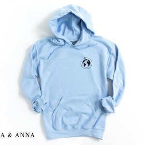 May include: A light blue hoodie with a small black graphic of the earth with airplanes flying around it.