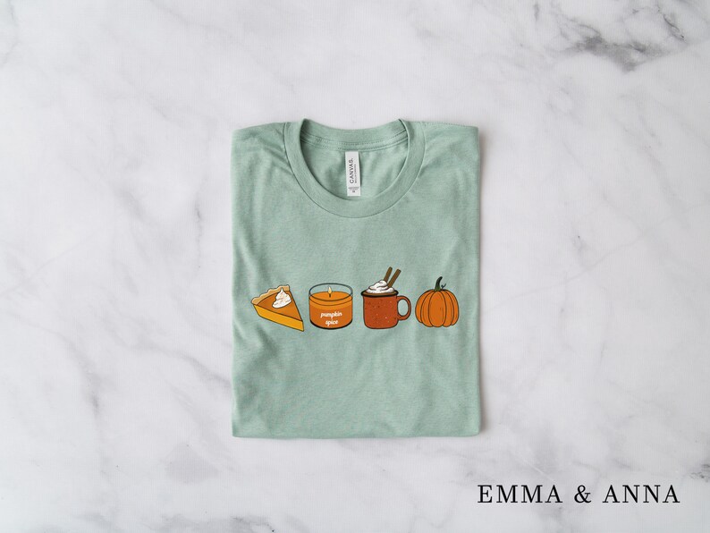 May include: A light green t-shirt with a graphic of a pumpkin, a candle that says "pumpkin spice", a mug of hot chocolate with whipped cream, and a slice of pumpkin pie.